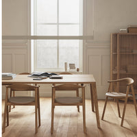 Light wood dining table with beige cushions and natural wood chairs, featuring a minimalist, neutral color palette.