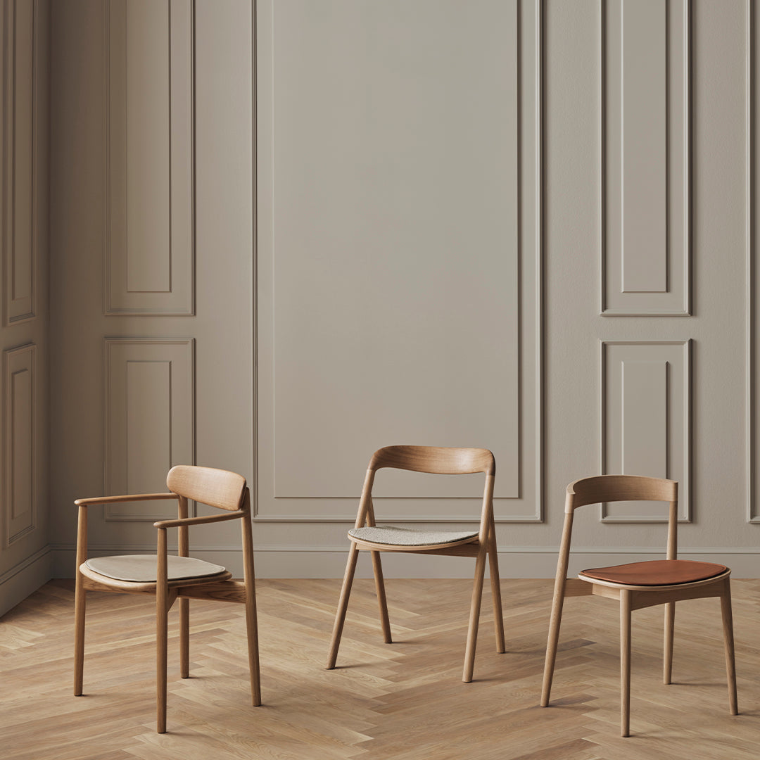 Three wooden chairs in warm tones with smooth finishes against a soft, neutral background. Stylish and modern design.