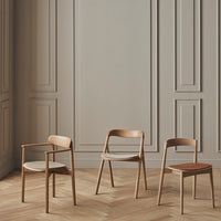 Three wooden chairs in warm tones with smooth finishes against a soft, neutral background. Stylish and modern design.