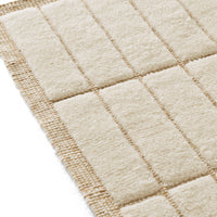 Beige textured rug with a grid pattern and a natural jute border. Soft, cozy design for modern interiors.