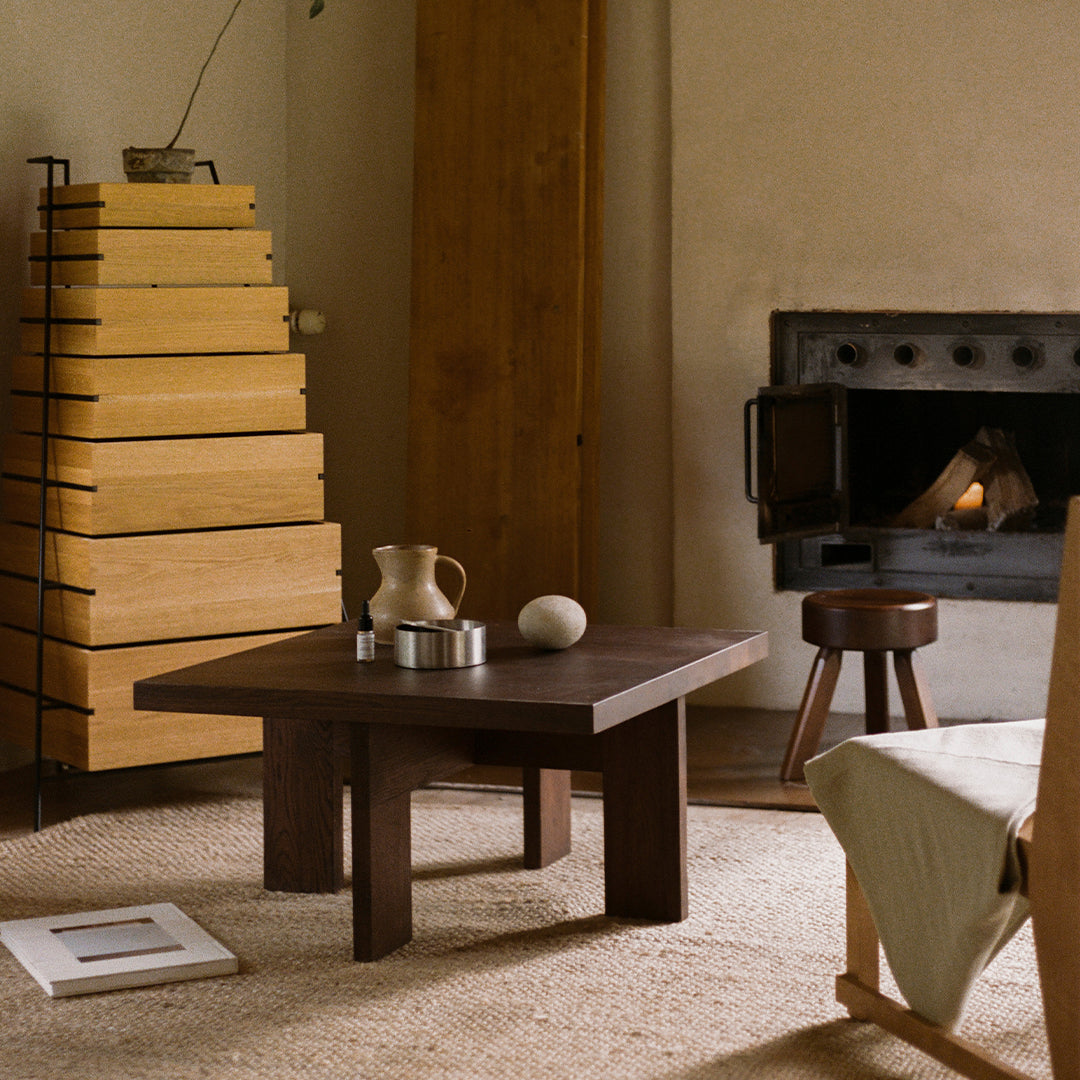 Dark wooden coffee table with minimalist design, surrounded by natural beige tones and warm wood accents.