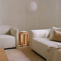 Light beige sofas with soft textures, warm wooden side table, and minimalistic decor create a cozy, neutral living space.