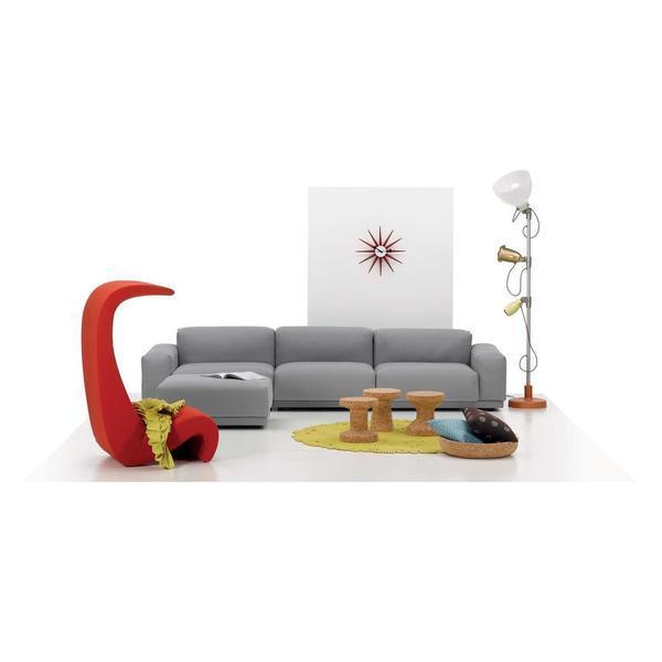 Contemporary living room with a gray sofa, vibrant red accent chair, yellow circular rug, and playful decor elements.