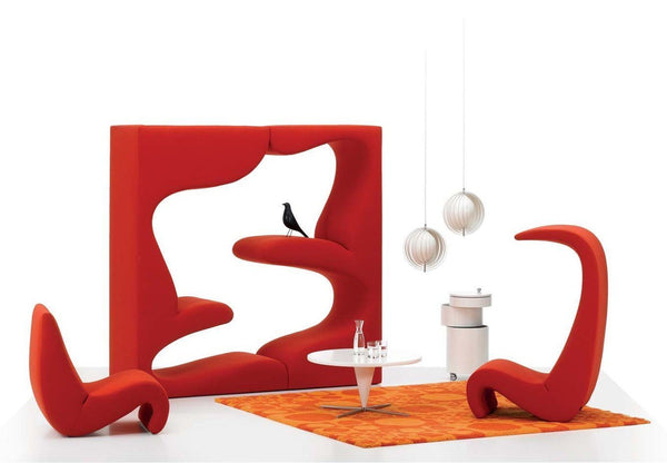 Bold red seating and partition with curved designs, complemented by an orange patterned rug and white accents.