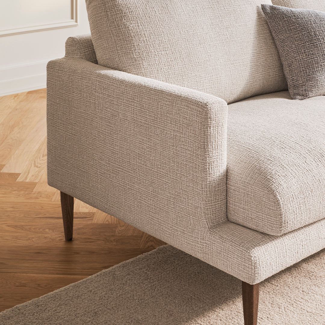 Light beige textured fabric sofa with a minimalist design and dark wood legs, pairing well with neutral tones.