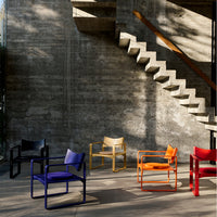 Colorful chairs in black, purple, yellow, orange, and red arranged against a minimalist concrete backdrop.