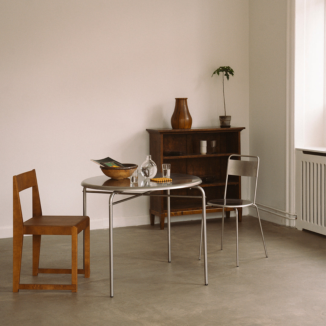Stylish wooden chair and chrome table, featuring neutral tones and minimalistic design in a modern interior setting.