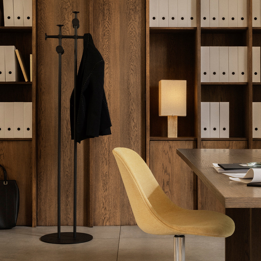 Black coat rack with a yellow chair against a warm wood backdrop, featuring white storage boxes and soft lighting.
