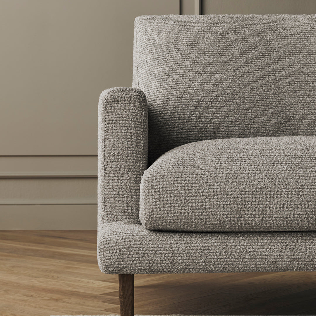 Gray textured sofa with a subtle pattern, complemented by natural wood legs, set against a neutral background.