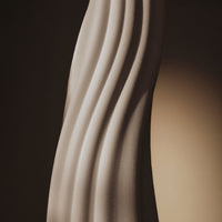 Elegant beige sculpture with flowing wave patterns and soft shadows creating a sophisticated design.