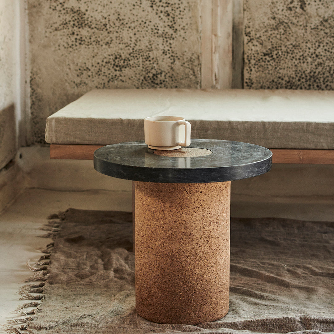 Cork and black marble round side table, minimalist design with neutral tones and natural textures.