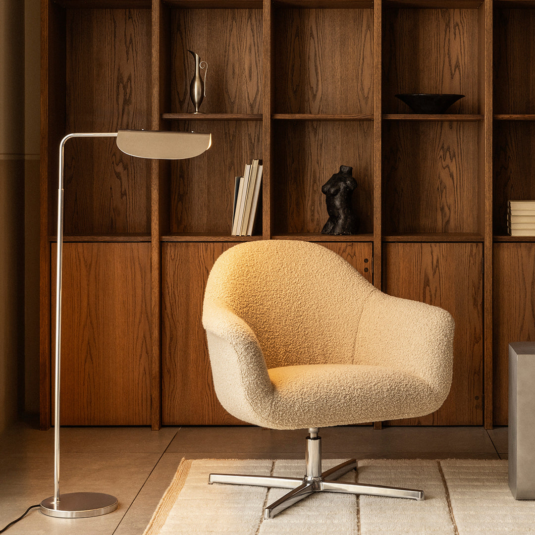 Cozy beige armchair with a soft, textured finish, paired with a sleek metallic floor lamp. Stylish modern decor.