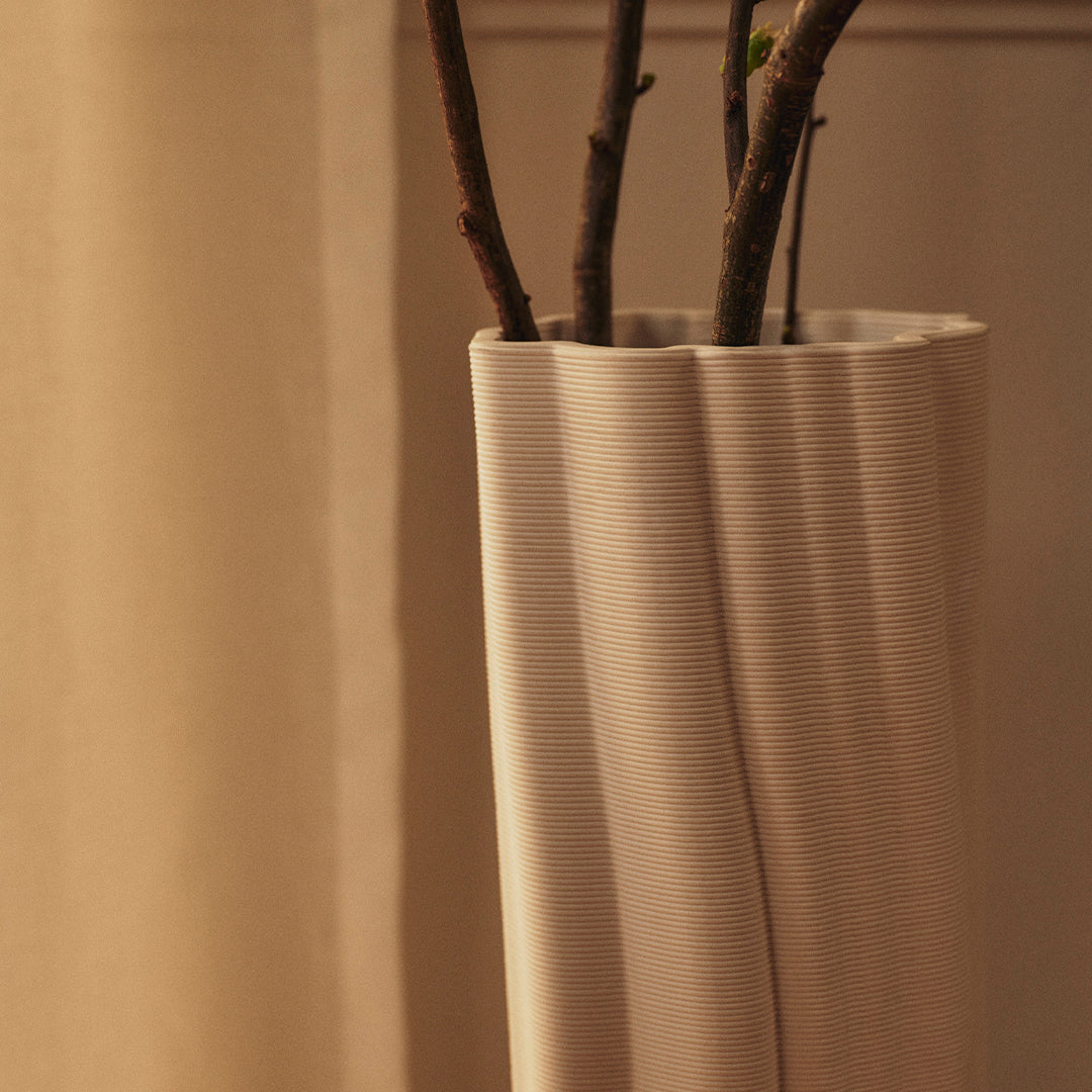 Elegant beige vase with subtle wavy texture, displaying natural branches for a minimalist aesthetic.