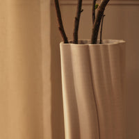 Elegant beige vase with subtle wavy texture, displaying natural branches for a minimalist aesthetic.