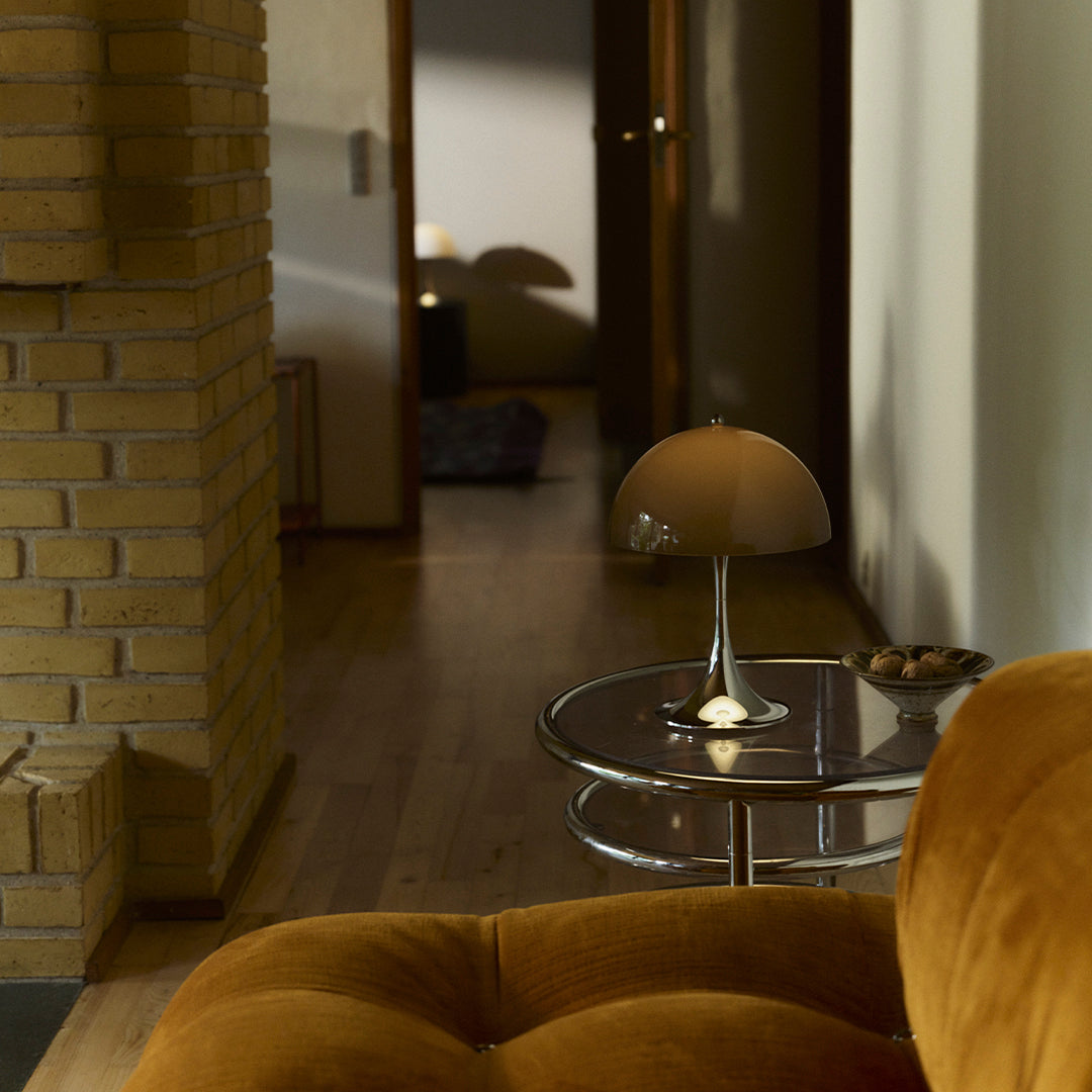 Soft orange velvet sofa, sleek glass side table with a modern lamp, warm wood tones, and neutral walls.