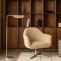 Beige textured chair with silver metallic base, set against rich wooden bookshelf backdrop. Modern and cozy aesthetic.