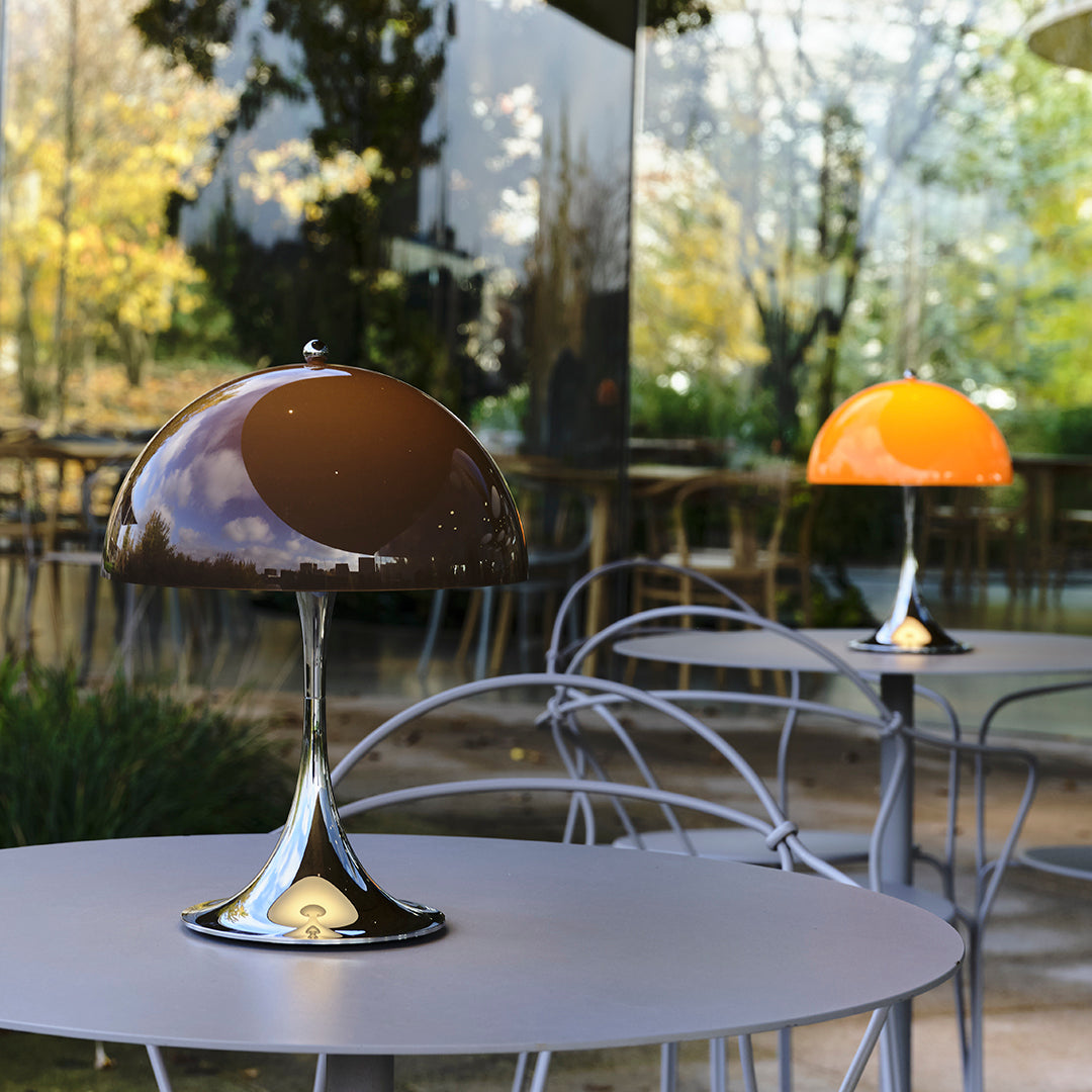 Brown and orange dome lamps on modern tables, featuring sleek chrome bases and vibrant color contrast in an outdoor setting.