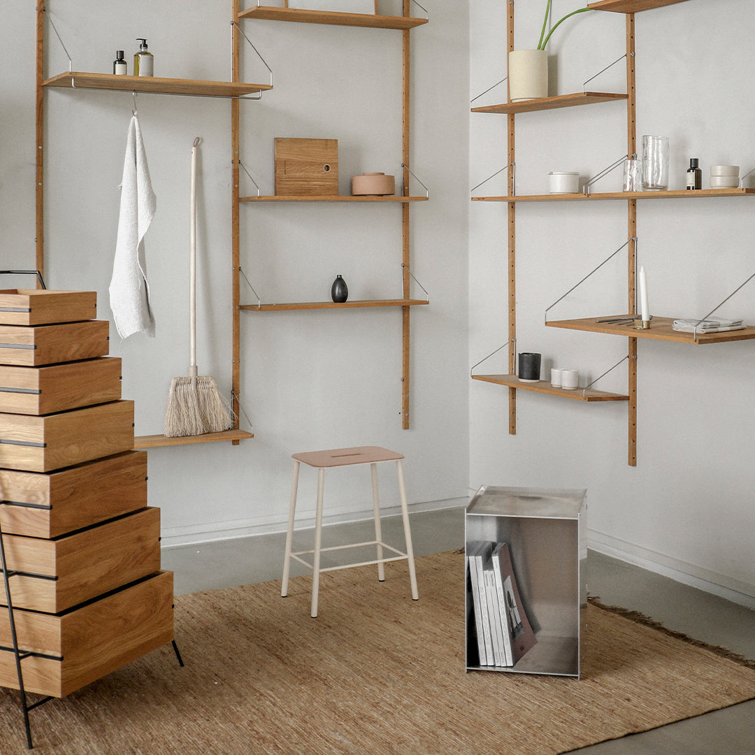 Modern interior with wooden shelves, beige rug, white walls, and a minimalist color palette featuring natural textures.