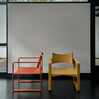 Red metal chair and natural wood chair in minimalistic setting, showcasing vibrant colors and clean lines.