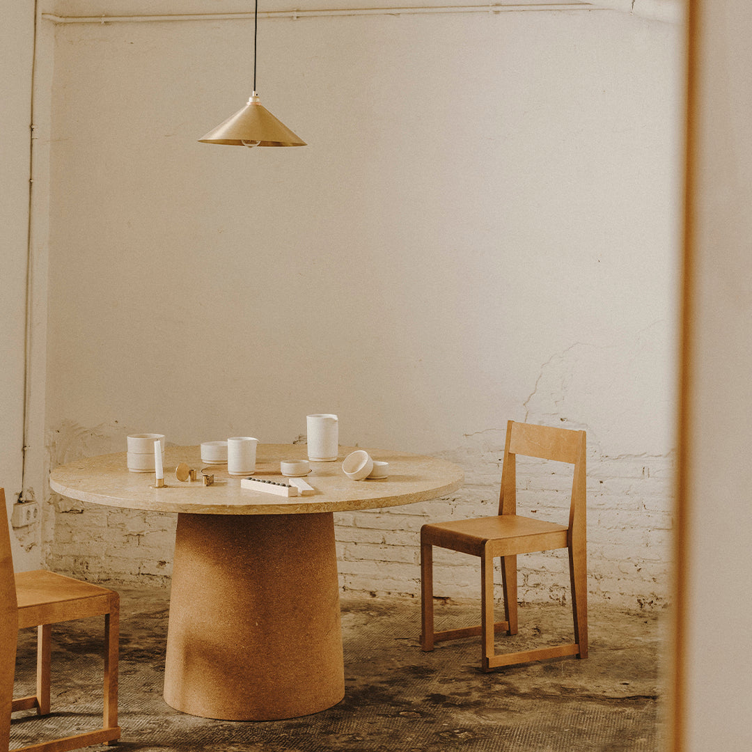 Natural wood tones and a minimalist design create a warm, inviting dining space with a round table and simple chairs.