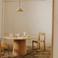 Natural wood tones and a minimalist design create a warm, inviting dining space with a round table and simple chairs.