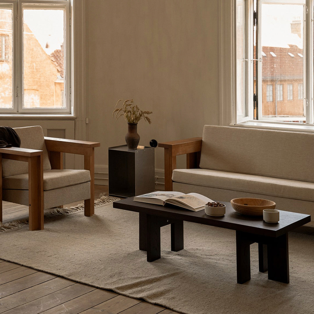 Neutral-toned living room featuring beige sofas, a dark wood coffee table, and natural textures in a warm atmosphere.