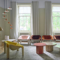 A vibrant seating area featuring orange, pink, and yellow hues with soft fabrics and geometric patterns.