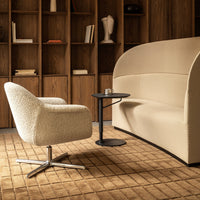 Cream-colored boucle armchair with a smooth beige sofa and a sleek black side table on a textured tan rug.