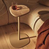 Light beige side table with a smooth, rounded top and a warm, neutral base, set against a cozy, textured background.