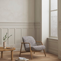 Light gray upholstered chair with a subtle texture, surrounded by neutral tones and natural wood accents.