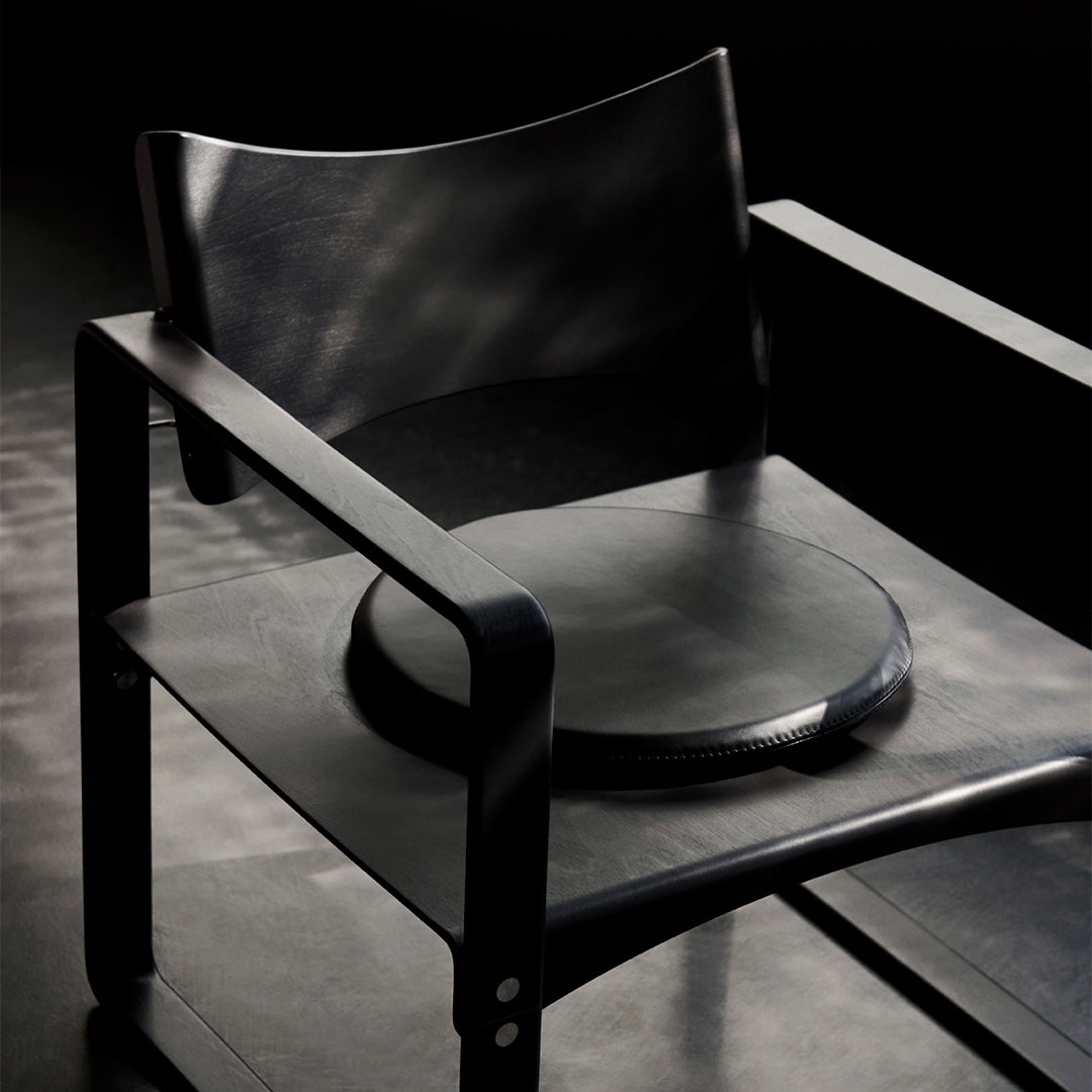 Stylish black chair with smooth, rounded seat and minimalistic design, featuring sleek lines and a modern aesthetic.