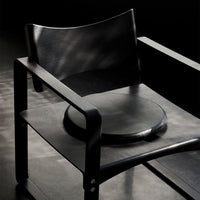 Stylish black chair with smooth, rounded seat and minimalistic design, featuring sleek lines and a modern aesthetic.