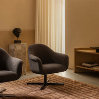 Contemporary dark gray swivel chairs on a textured beige rug, set against warm, neutral-toned walls.