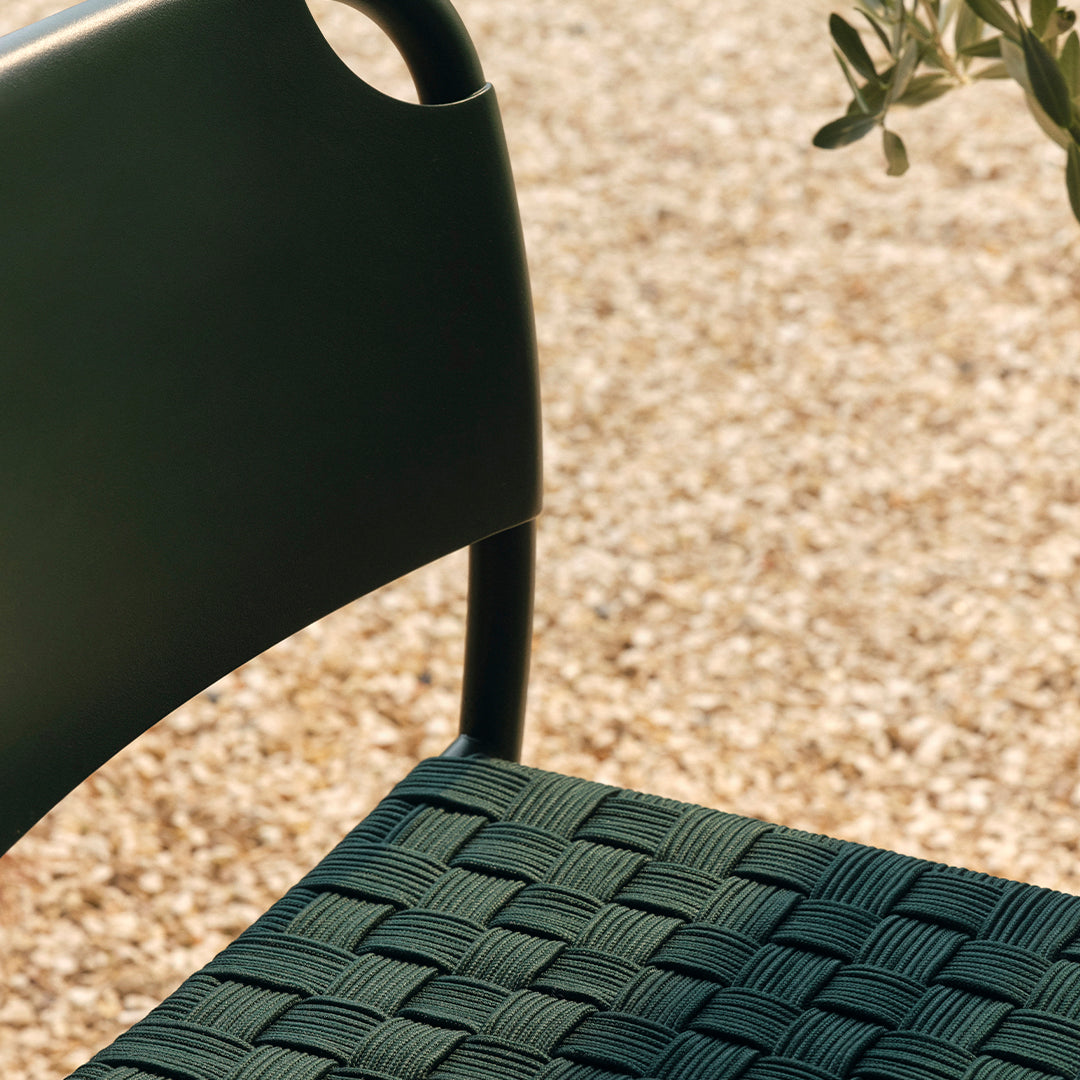 Green woven chair seat with textured pattern, complemented by a sleek black frame. Perfect for modern outdoor settings.