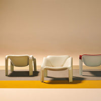 Set of three modern chairs in cream, red, and gray against a warm pastel background with bold geometric patterns.