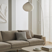Neutral beige sofa with a gray accent pillow, surrounded by soft white walls and natural light. Modern minimalist aesthetic.