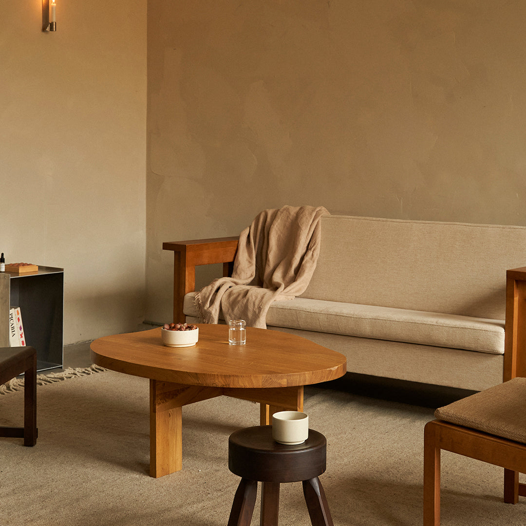 Cozy living room with beige sofa, light wood furniture, soft brown throw, and neutral-toned decor for a warm aesthetic.