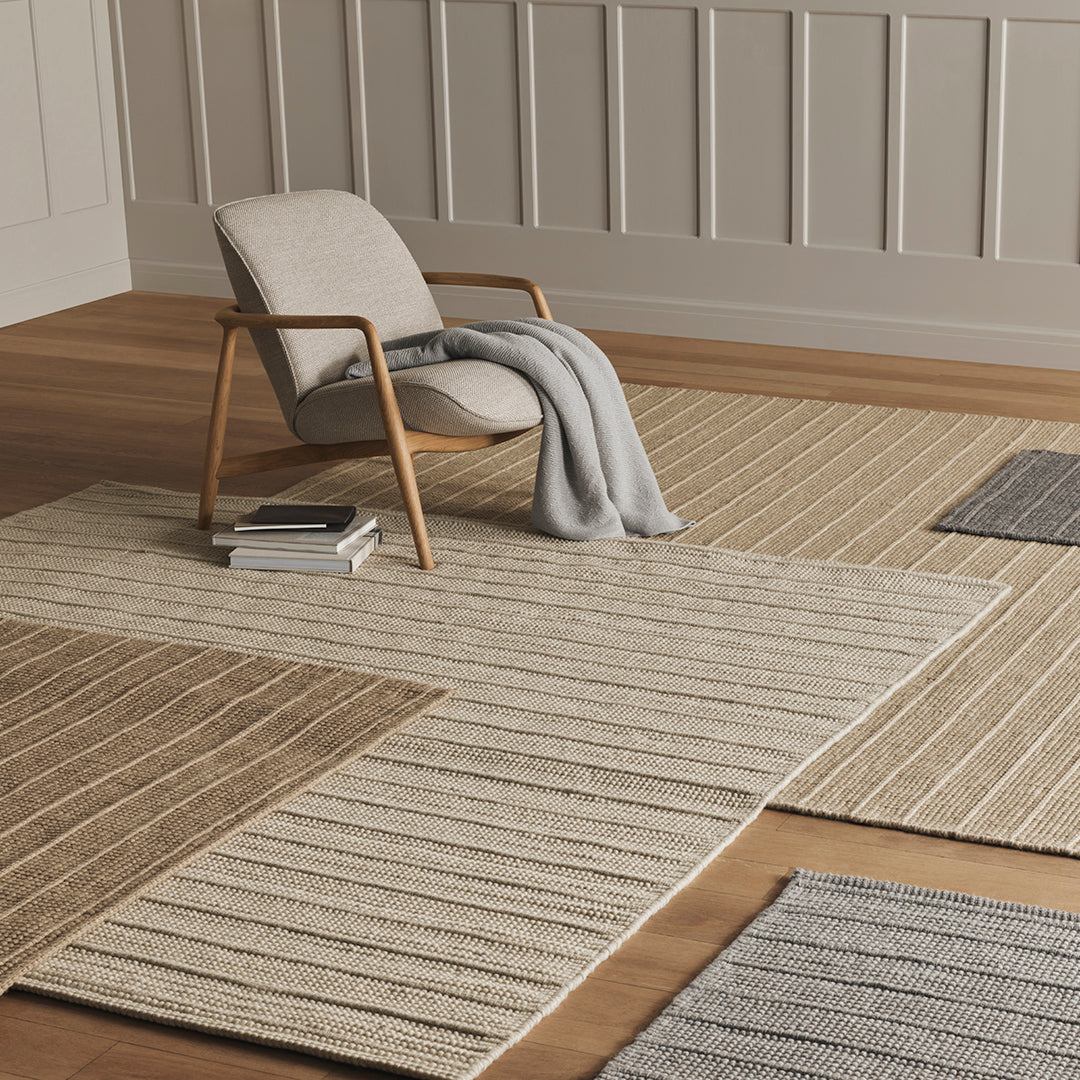 Beige and gray striped area rugs on wooden floor, creating a textured, neutral-toned pattern in a modern setting.