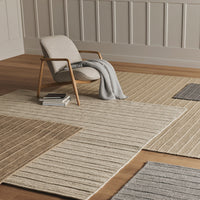 Beige and gray striped area rugs on wooden floor, creating a textured, neutral-toned pattern in a modern setting.