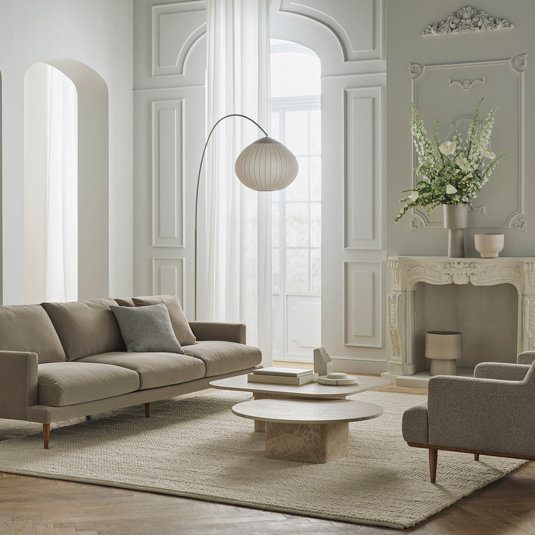 Modern beige sofa with light gray accent chairs, neutral rug, and soft textured patterns in a bright, airy living room.