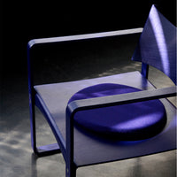 Modern chair featuring deep purple fabric and sleek geometric patterns, with a contrasting circular cushion.