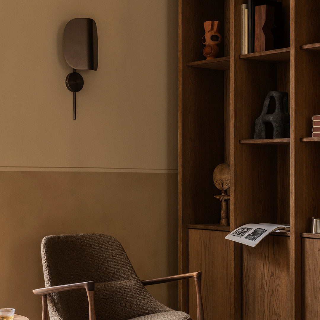 Warm beige wall, rich wooden shelves, and textured brown chair create a cozy, inviting interior scene.