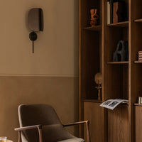 Warm beige wall, rich wooden shelves, and textured brown chair create a cozy, inviting interior scene.