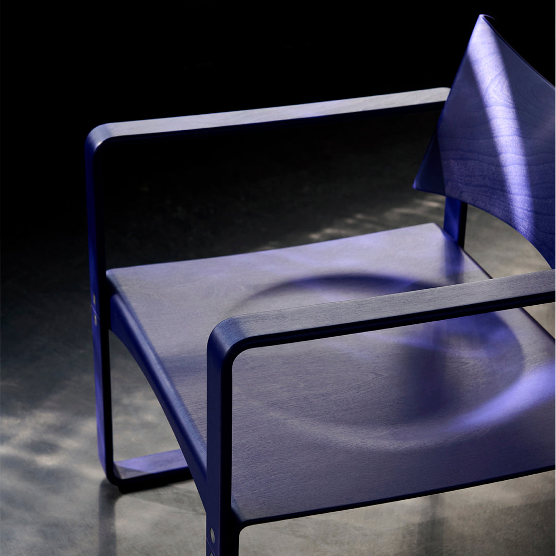 Modern chair in deep purple with sleek lines and minimalist design, featuring unique light patterns on the surface.