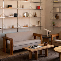 Light gray sofa with wooden frame, complemented by natural wood tables and neutral decor in a modern living space.