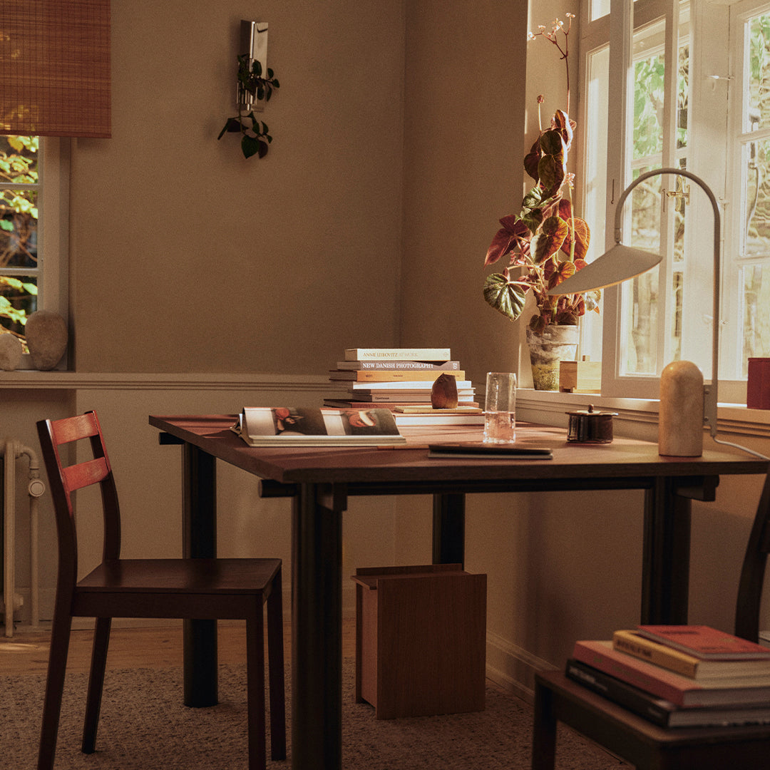 Warm neutral tones with wooden textures, complemented by rich maroon accents and soft natural light.