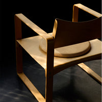 Light wood chair with a smooth, natural finish and minimalist design against a dark background.