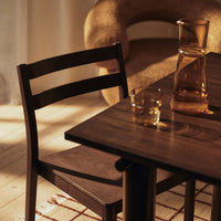 Dark wood chair and table with warm tones, featuring a textured surface and soft, cozy background elements.