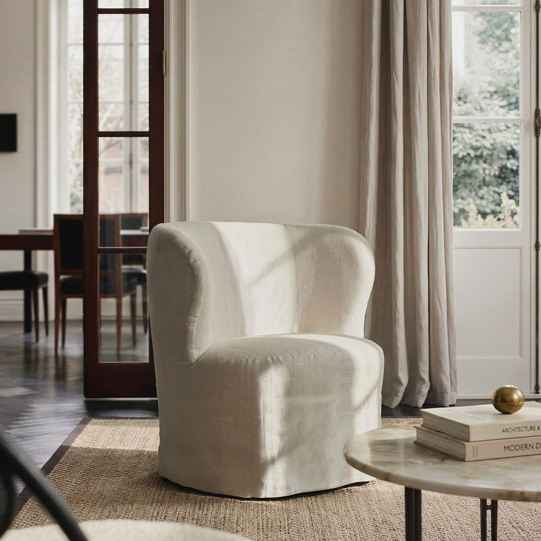 Soft white boucle armchair with a rounded silhouette, set against a neutral-toned room with natural light.