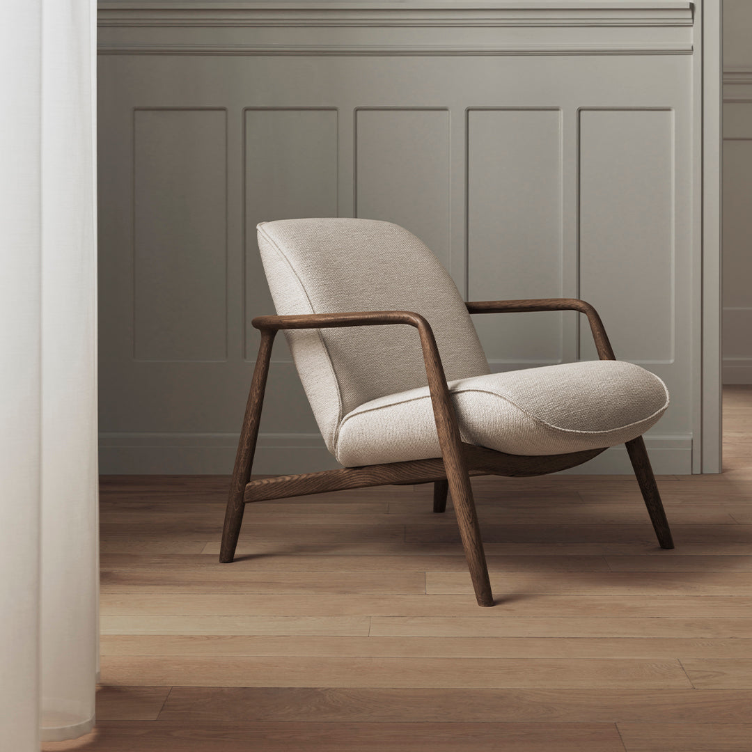 Beige upholstered chair with a smooth, minimalist design and dark wooden frame, set against a neutral backdrop.